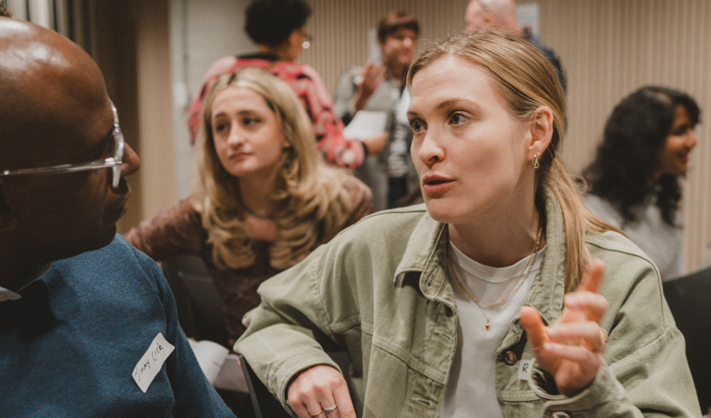 Two people have a discussion amongst a larger group