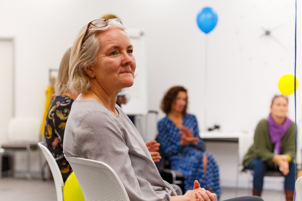 Focus on person listening who is sat in a circle of people in chairs