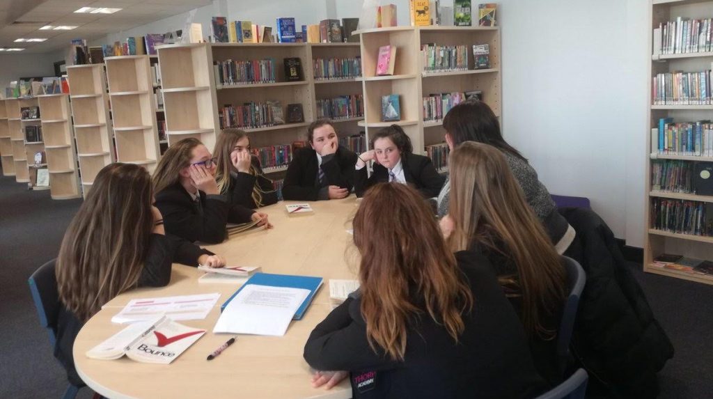 Group of school children sat around a table working with Melanie Cornish, founder of Bringing Words to Life 