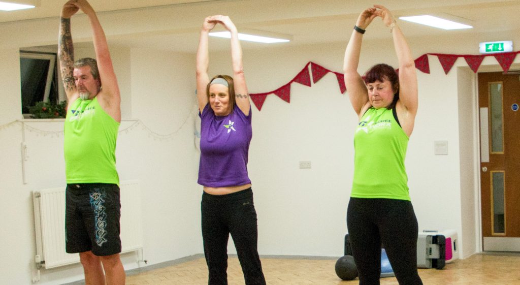 A group of people stretching as part of a Bodeeworx session