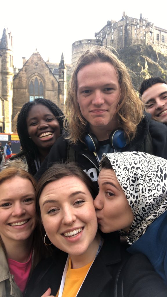 A selfie of 6 of the young programme participants smiling, with Edinburgh castle in the background