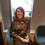 Claire Prosho, founder of Claire's Transgender Talks, sitting down and smiling for the camera.