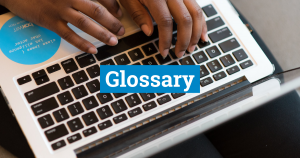 Laptop keyboard with person typing, from above. Blue textbox with white text reads: Glossary. Photo credit: Women of Colour in Tech