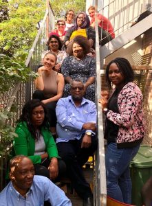 Felicia Boshorin (middle right of stairwell wearing blue floral dress) with her team at Central Southwark Community Hub at an away day in 2019